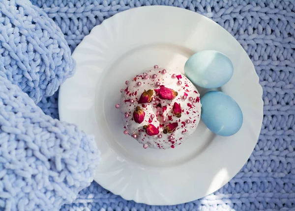 Easter bread, cake and eggs with decor of flowers, beads and nuts. Blue knitted plaid. The concept of the Easter holidays and decor.