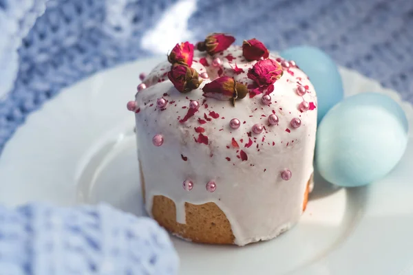 Easter bread, cake and eggs with decor of flowers, beads and nuts. Blue knitted plaid. The concept of the Easter holidays and decor.