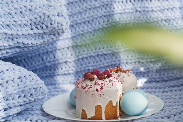 Easter bread, cake and eggs with decor of flowers, beads and nuts. Blue knitted plaid. The concept of the Easter holidays and decor.