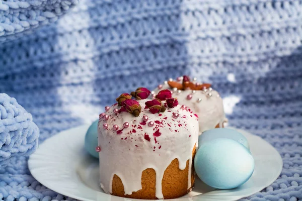 Easter bread, cake and eggs with decor of flowers, beads and nuts. Blue knitted plaid. The concept of the Easter holidays and decor.