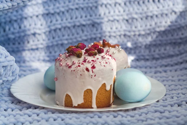 Easter bread, cake and eggs with decor of flowers, beads and nuts. Blue knitted plaid. The concept of the Easter holidays and decor.