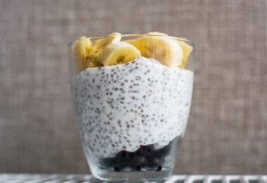 Arka plan ve iki bardak puding chia, kuşüzümü ve taze muz parçaları. Faydalı ve lezzetli, vitaminli kahvaltı..