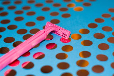 Konfeti ve pembe kadın jiletiyle parlak bir arka plan. Tıraş makinesi için jilet. Kişisel hijyenik rutin için keskin jiletler.