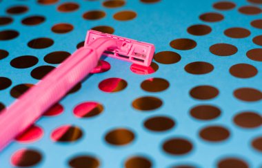 Konfeti ve pembe kadın jiletiyle parlak bir arka plan. Tıraş makinesi için jilet. Kişisel hijyenik rutin için keskin jiletler.