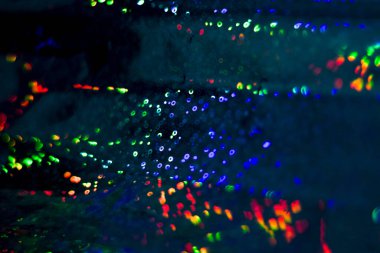 Dolu, çok renkli, gökkuşağı bokeh ve röfleli koyu soyut arkaplan.