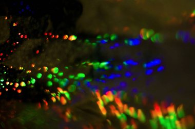 Dolu, çok renkli, gökkuşağı bokeh ve röfleli koyu soyut arkaplan.