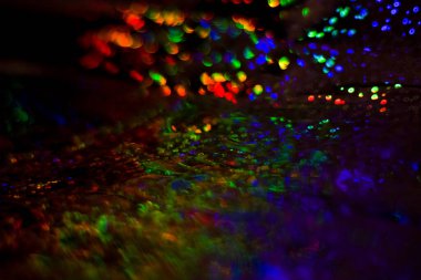 Dolu, çok renkli, gökkuşağı bokeh ve röfleli koyu soyut arkaplan.