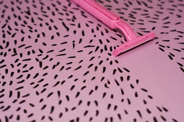 Pink background with marker drawn hairs and female razor for depilation.