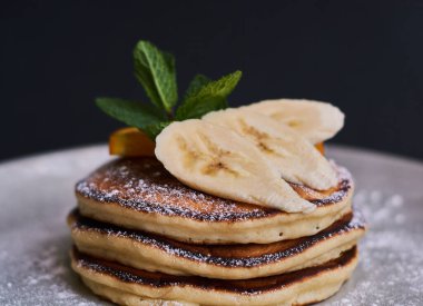 Portakal, muz, nane ve şeker tozuyla süslenmiş ev yapımı krep kahvaltısı..