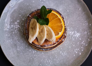 Portakal, muz, nane ve şeker tozuyla süslenmiş ev yapımı krep kahvaltısı..