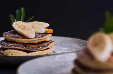 Portakal, muz, nane ve şeker tozuyla süslenmiş ev yapımı krep kahvaltısı..