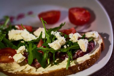 Peynir, roka, vişneli domates ve sosisli büyük boy çavdar ekmeği..