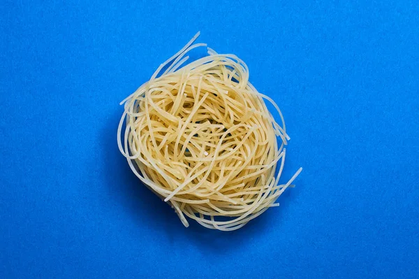 Blue background and Italian noodles, spaghetti, pasta of different forms of wheat in raw.