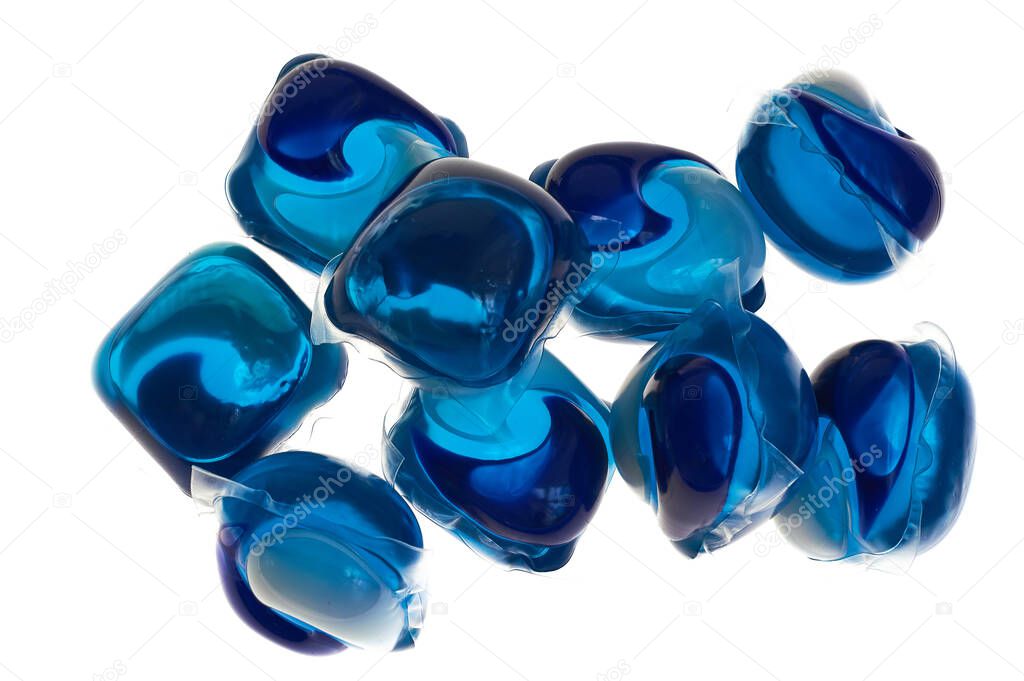 White isolated background and blue soluble capsules with liquid to remove stains from clothes in washing machine.