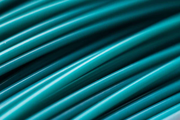 Turquoise wires, plastic coil in macro. Close-up of a strip of plastic in a reel of turquoise color.