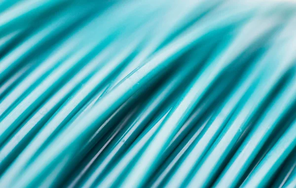 Turquoise wires, plastic coil in macro. Close-up of a strip of plastic in a reel of turquoise color.