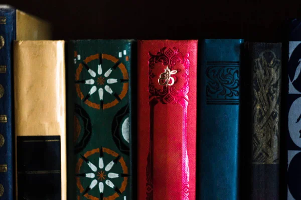 Multicolored books without titles on the bookshelf, the top of the books. Red, blue, yellow, green book with star pattern on bookshelf with dark background