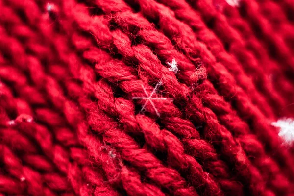 Macrophotography of snowflakes on a red knitted fabric with a large knit