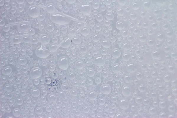 Drops of water on the cloudy glass. Spray on the whitish surface. Many small identical drops.