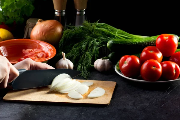 women's hands with a knife cut onions on a cutting Board