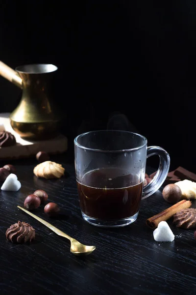 Hot coffee is poured into a transparent Cup from above. The hot steam coming from the mug.