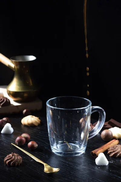 Hot coffee is poured into a transparent Cup from above. The hot steam coming from the mug.