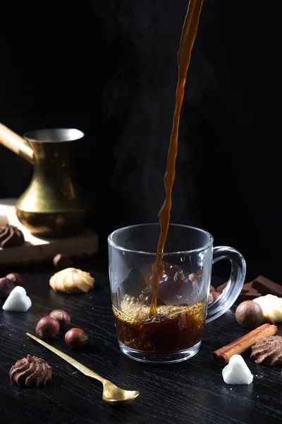 Hot coffee is poured into a transparent Cup from above. The hot steam coming from the mug