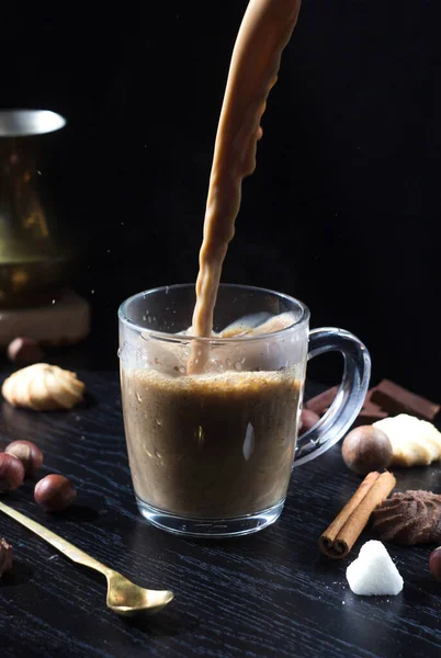 Hot coffee is poured into a transparent Cup from above. The hot steam coming from the mug