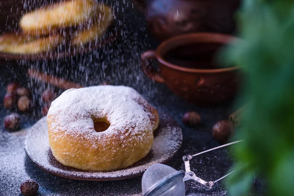 The doughnut is covered with powdered sugar. powdered sugar falls on top of the doughnut