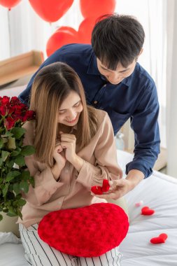 Genç ve gülümseyen Asyalı bir adam, sevgilisi mutlu ve heyecanlı bir yüzle genç ve güzel bir kadına yüzük kutusu veriyor ve açıyor. Aşk kavramı, zamanı paylaşmak ve düğün istemek..