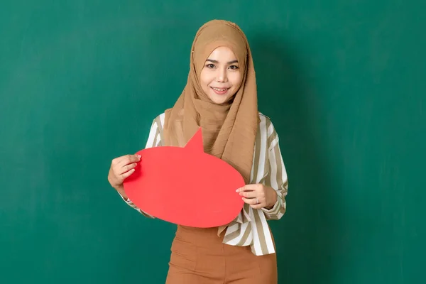 緑の壁に立つ若くて美しいアジア系イスラム教徒の女性は カラフルな空白のスピーチバブルを保持し 表示します 重要なメッセージのテキストを社会や公共に伝えるためのコンセプト — ストック写真