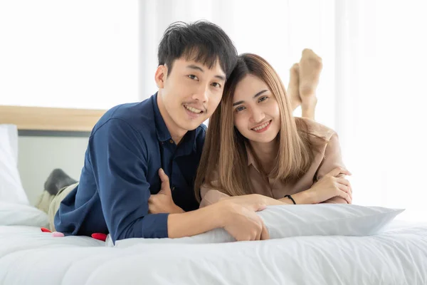 若くてかわいいアジアのカップルがベッドルームで一緒に寝そべって 幸せポーズのカメラを見ています 恋人のためのアイデアは プライベートの瞬間に一緒に楽しい時間を共有する テーマと結婚するための甘い概念 — ストック写真
