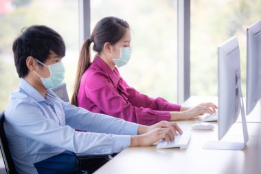 Erkek ve kadın iş adamları Corona 'yı korumak ve önlemek için cerrahi maske takarken ofiste birlikte çalışıyorlar, Cvid-19 virüs hastalığından. İş yerinde güvenlik sağlık hizmetleri kavramı.