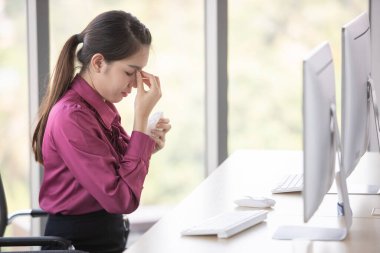 Ofis ve işyerindeki tehlikeli kirli hava ve virüs hastalıklarından korunmak için çalışan ve yüzüne cerrahi maske takan bir kadın. Hasta, hasta ya da acı çekiyor gibi görünüyor..