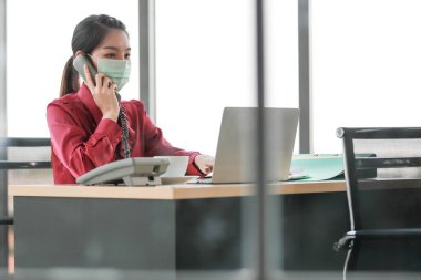 Ofis ve işyerindeki tehlikeli kirli hava ve virüs hastalıklarından korunmak için çalışan ve yüzüne cerrahi maske takan bir kadın. Günlük hayatta sağlıkla ilgili fikir.