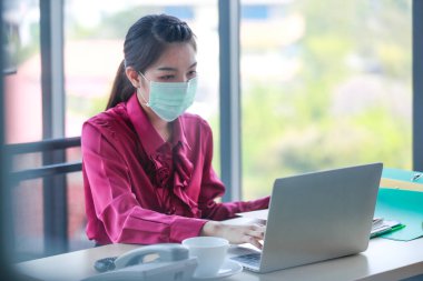 Ofis ve işyerindeki tehlikeli kirli hava ve virüs hastalıklarından korunmak için çalışan ve yüzüne cerrahi maske takan bir kadın. Hayatım, günlük hayatta sağlıkla ilgilendiğin için..