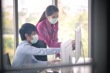 Erkek ve kadın iş adamları Corona 'yı korumak ve önlemek için cerrahi maske takarken ofiste birlikte çalışıyorlar, Cvid-19 virüs hastalığından. İş yerinde güvenlik sağlık hizmetleri kavramı.