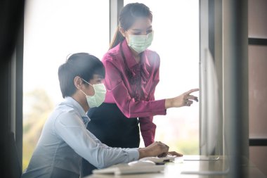 Erkek ve kadın iş adamları Corona 'yı korumak ve önlemek için cerrahi maske takarken ofiste birlikte çalışıyorlar, Cvid-19 virüs hastalığından. İş yerinde güvenlik sağlık hizmetleri kavramı.