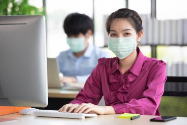 Erkek ve kadın iş adamları Corona 'yı korumak ve önlemek için cerrahi maske takarken ofiste birlikte çalışıyorlar, Cvid-19 virüs hastalığından. İş yerinde güvenlik sağlık hizmetleri kavramı.