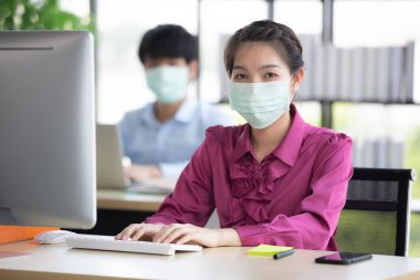 Erkek ve kadın iş adamları Corona 'yı korumak ve önlemek için cerrahi maske takarken ofiste birlikte çalışıyorlar, Cvid-19 virüs hastalığından. İş yerinde güvenlik sağlık hizmetleri kavramı.