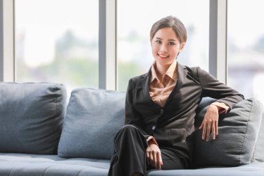 Kot pantolon giymiş güzel Asyalı bir kadının portresi. Gülümsüyor ve elini tutuyor. Kırmızı arka planda izole edilmiş mutlu yüzüyle..