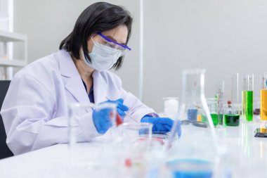 Laboratuvarda laboratuvar aletleri ve ekipmanlarıyla testlerin çözümünü bulmakla meşgul kadın araştırmacı. Yeni yararlı bilgi için sağlık sektöründe çalışan kişiler için kavram.