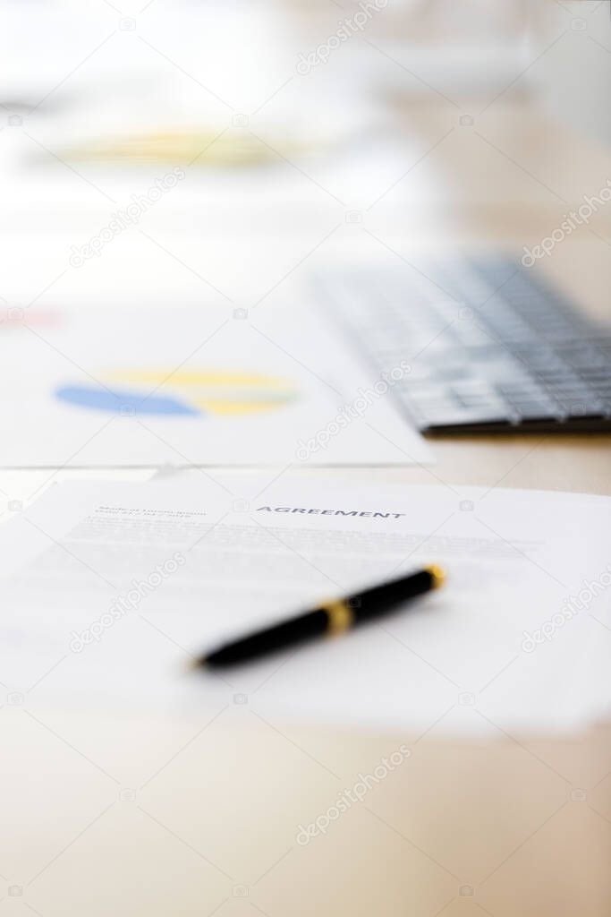 Document and pen at foreground, blurred computer and keyboard are background, concept for nobody in modern office.