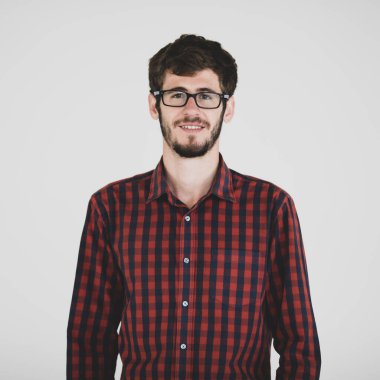 Gözlüklü, gri arka planda duran, kendine güvenen ve kameraya mutlu bakan genç ve yakışıklı bir adamın portresi. Kendine güveni olan beyaz adamın yarı vücut fotoğrafı..