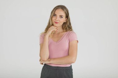 Gri arka planda kendine güvenen ve mutlu bir şekilde kameraya bakan, sıradan giysili genç ve güzel bir kadının portresi. Kendine güvenen beyaz kızın yarı vücut fotoğrafı..