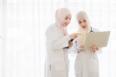 İki çekici, genç, güzel, Müslüman kadın doktor yüzünü tesettür elbisesiyle örterek tablet bilgisayardaki vakaları tartışıyor ve kullanıyor. Modern ısıtma sektöründe çalışan tıbbi çalışanlara bayılıyorum..