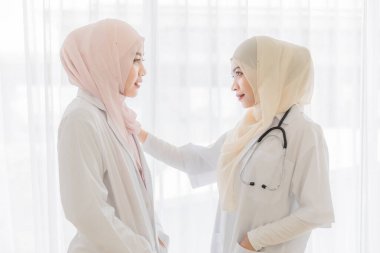 Çekici, genç, güzel, Müslüman kadın doktor yüzünü tesettür elbisesiyle örterek doktor arkadaşıyla konuşuyor. Modern ısıtma sektöründe güvenilir tıbbi çalışanlar için sevgili..