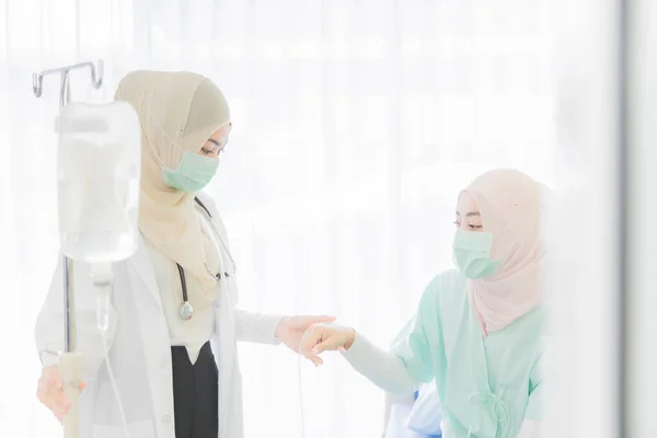 衛生保護マスクを着用したイスラム教徒の女性医師は 顔に注意を払い 病院の部屋で優しい方法で女性患者と話をする ヘルスケアとヘルスケアビジネスの仕事に理想的な — ストック写真