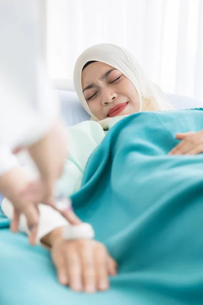 ヒジャーブを身に着けているイスラム教徒の女性患者は 病院でベッドの上に横たわり 注射器と針を見てください 彼女の顔は恐怖と恐怖を表現している ヘルスケアビジネスサービスの考え方 — ストック写真