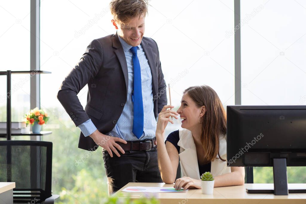 A handsome Caucasian male boss is having fun chatting and teasing with beautiful businesswoman under a not stress work environment.